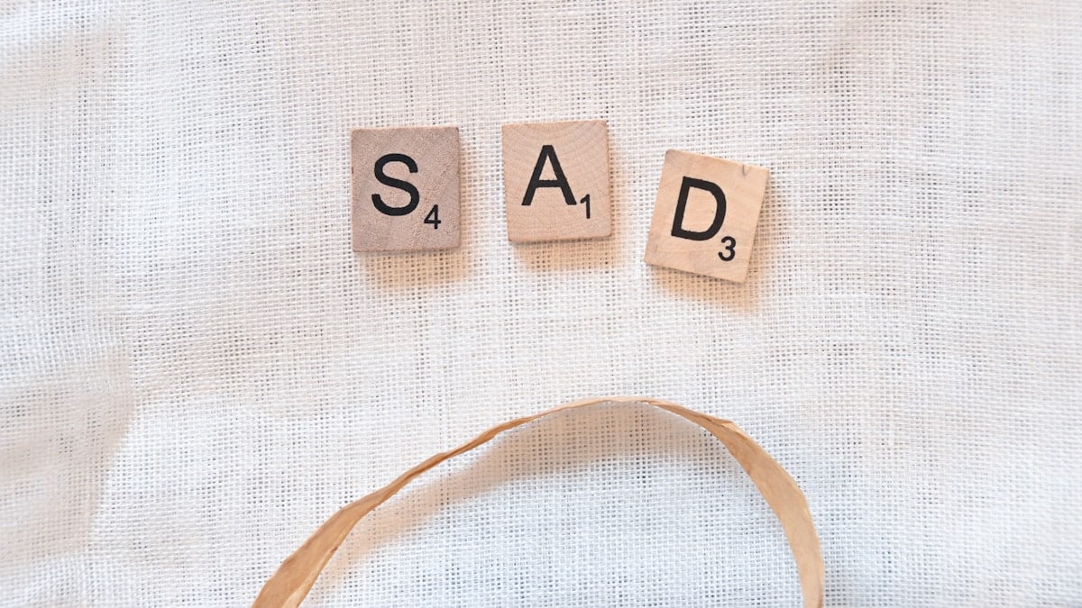 scrabble tiles spelling sad and sad on a white background